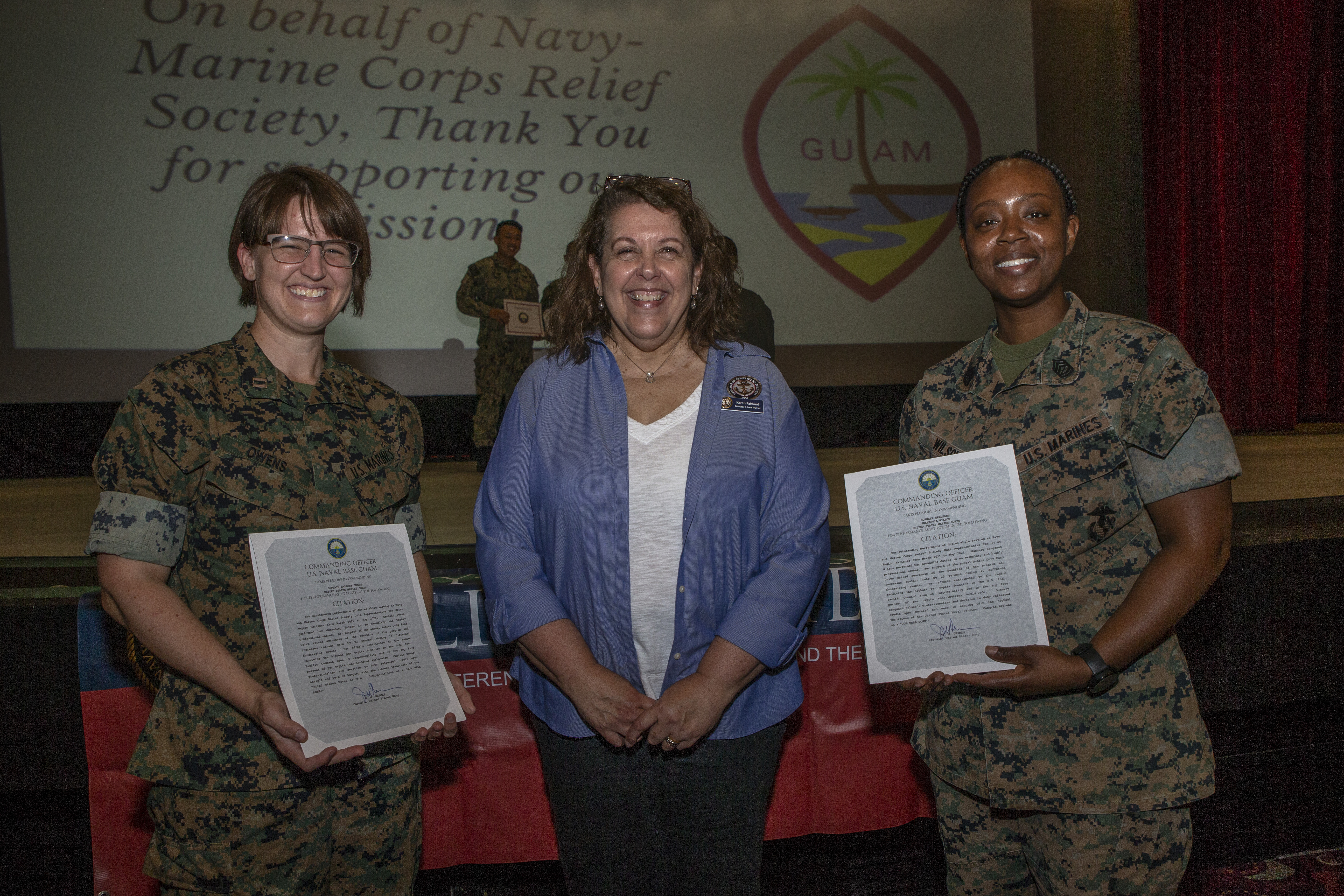 U.S. Marine Corps Capt. Mallory Owens, the Marine Corps Base (MCB) Camp Blaz Adjutant, left, and Gunnery Sgt. Shantavia Wilson, the MCB Camp Blaz Protocol Chief, right, pose for a photograph with Karen Fahland, the Navy Marine Corps Relief Society (NMCRS) Guam Director, at an awards ceremony on U.S. Naval Base Guam, May 25, 2021.