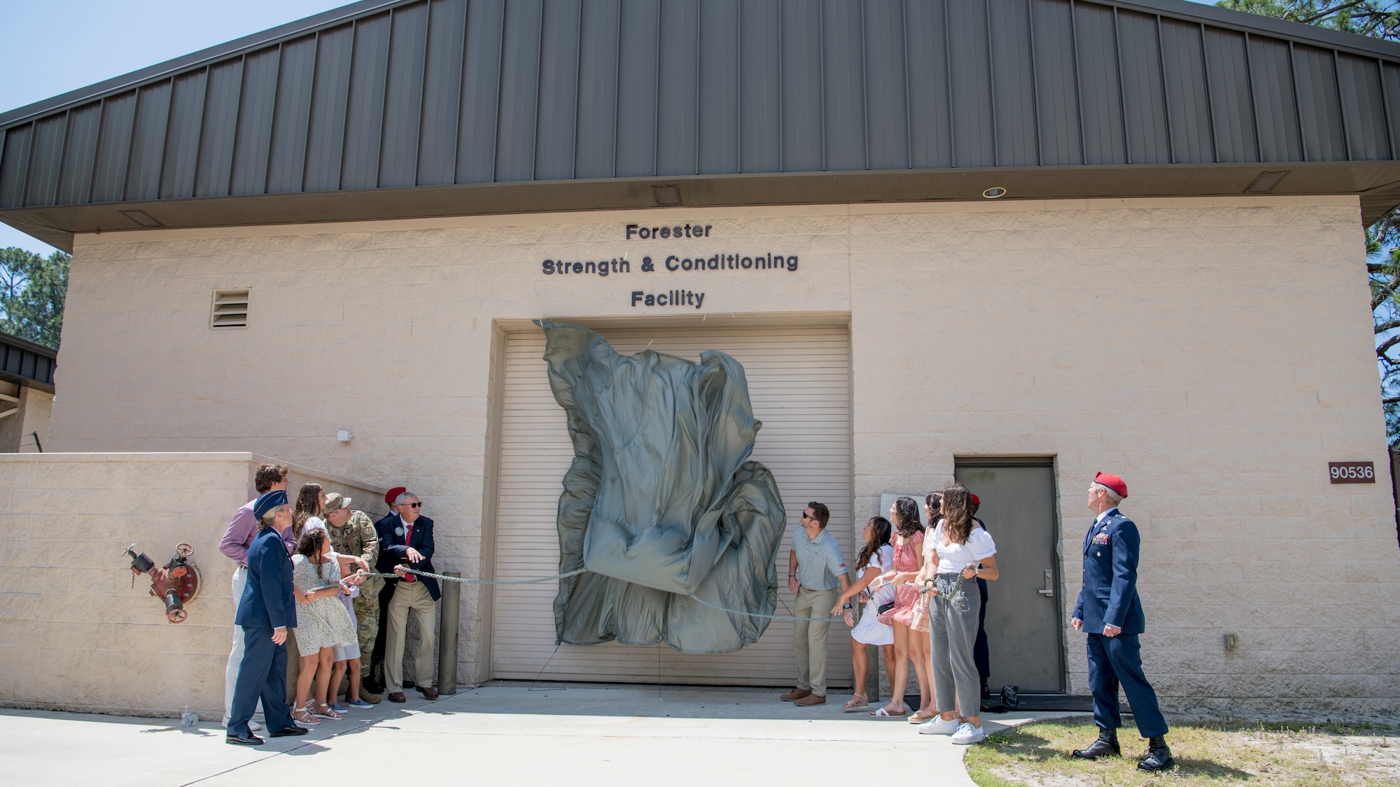 Family members of U.S. Air Force Senior Airman Mark Forester unveil the Forester Strength and Conditioning Facility during a ceremony at Hurlburt Field, Florida, May 27, 2021.