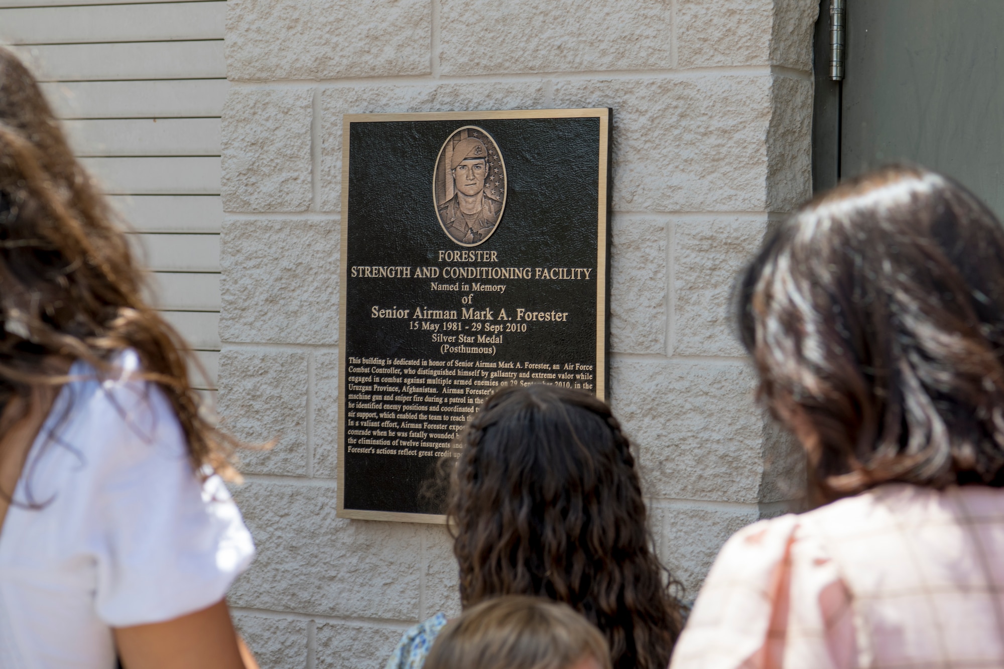 Family members of U.S. Air Force Senior Airman Mark Forester read a memorial plaque after a ceremony at Hurlburt Field, Florida, May 27, 2021.