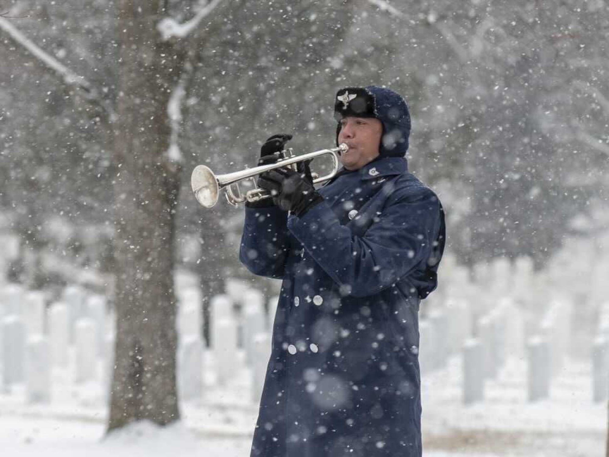 A snowstorm does not stop Master Sgt. (sel) Michael Ramos from sounding Taps during a funeral held at Arlington National Cemetery (U.S. Air Force photo by Technical Sgt. Joshua Freely).
