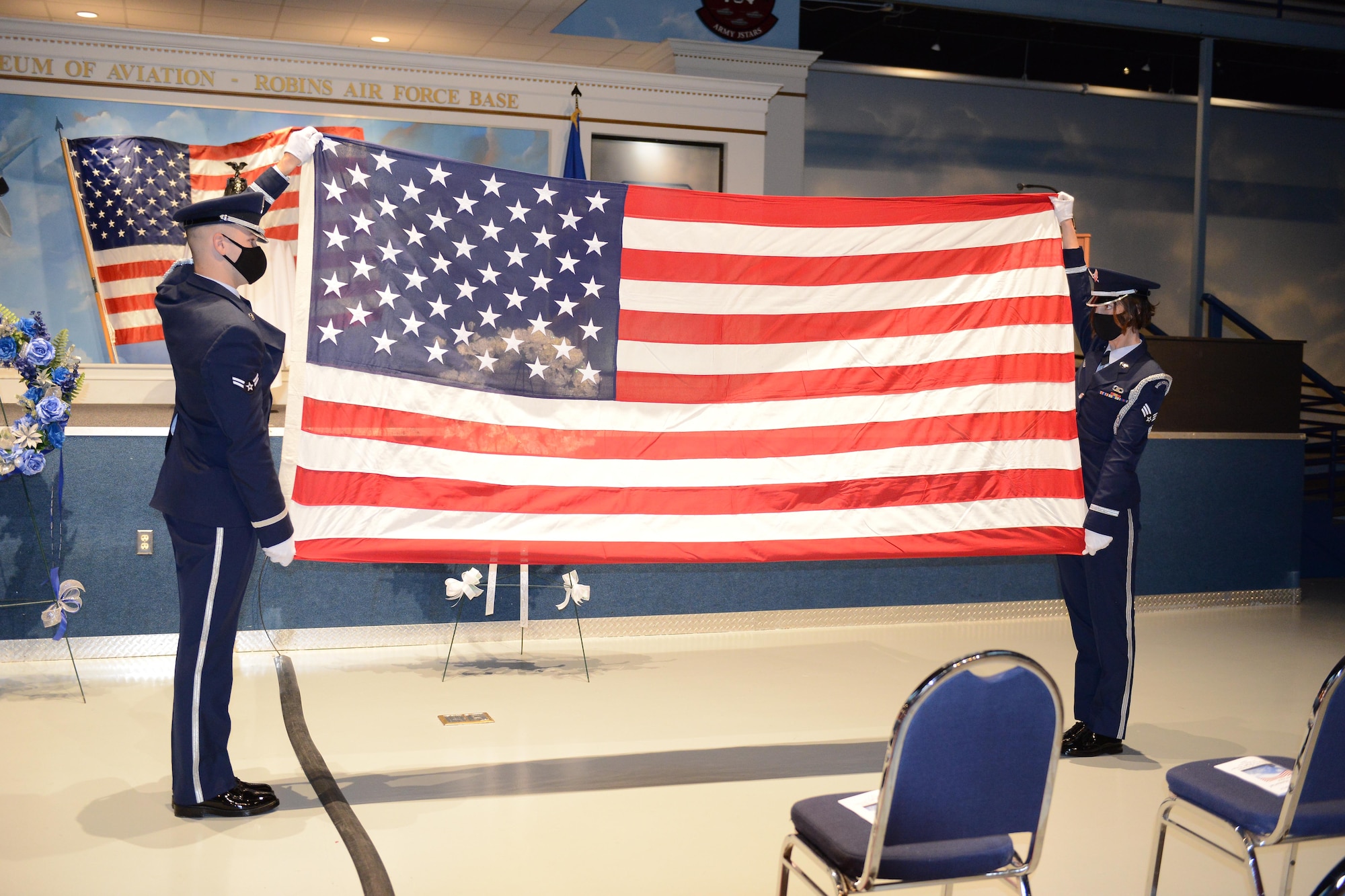 Photo shows two people holding unfurled flag up.