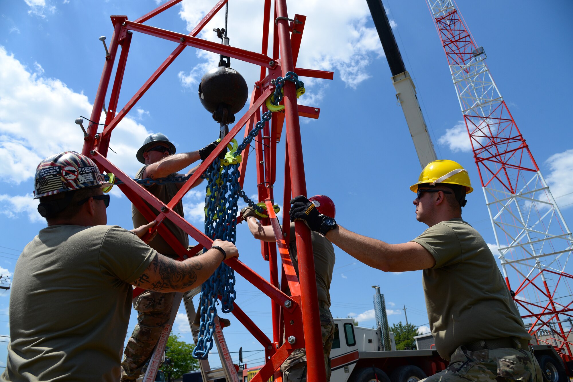 An image of Airmen Airmen with the Massachusetts and Pennsylvania Air National Guard attaching lifting straps to the top section of a radio communications tower.