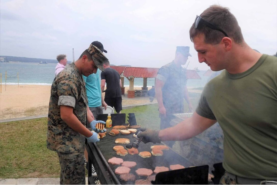 部隊の隊員や英会話クラスの受講生など、１００人近くを招いて、自前でBBQを開催し、パティをBBQで焼くブライアン・ゴフ中尉、２０２１年３月２４日、米海兵隊基地キャンプ・シュワブ