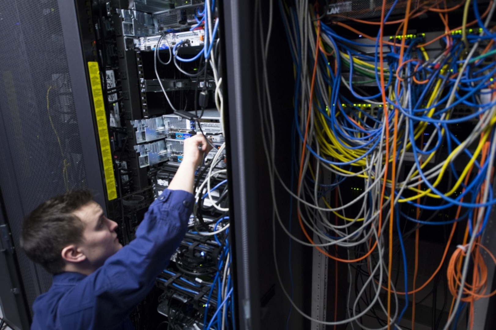 ALEXANDRIA, Va. - A Coast Guard Information Systems Technician adjusts cables inside a server room at the Telecommunication and Information Systems Command (TISCOM) Jan. 24, 2013. ITs are responsible for establishing and maintaining Coast Guard computer systems, analog and digital voice systems (telephones and voicemail), and installing and maintaining the physical network infrastructure that ties the systems together. U.S. Coast Guard photo by Petty Officer 2nd Class Etta Smith