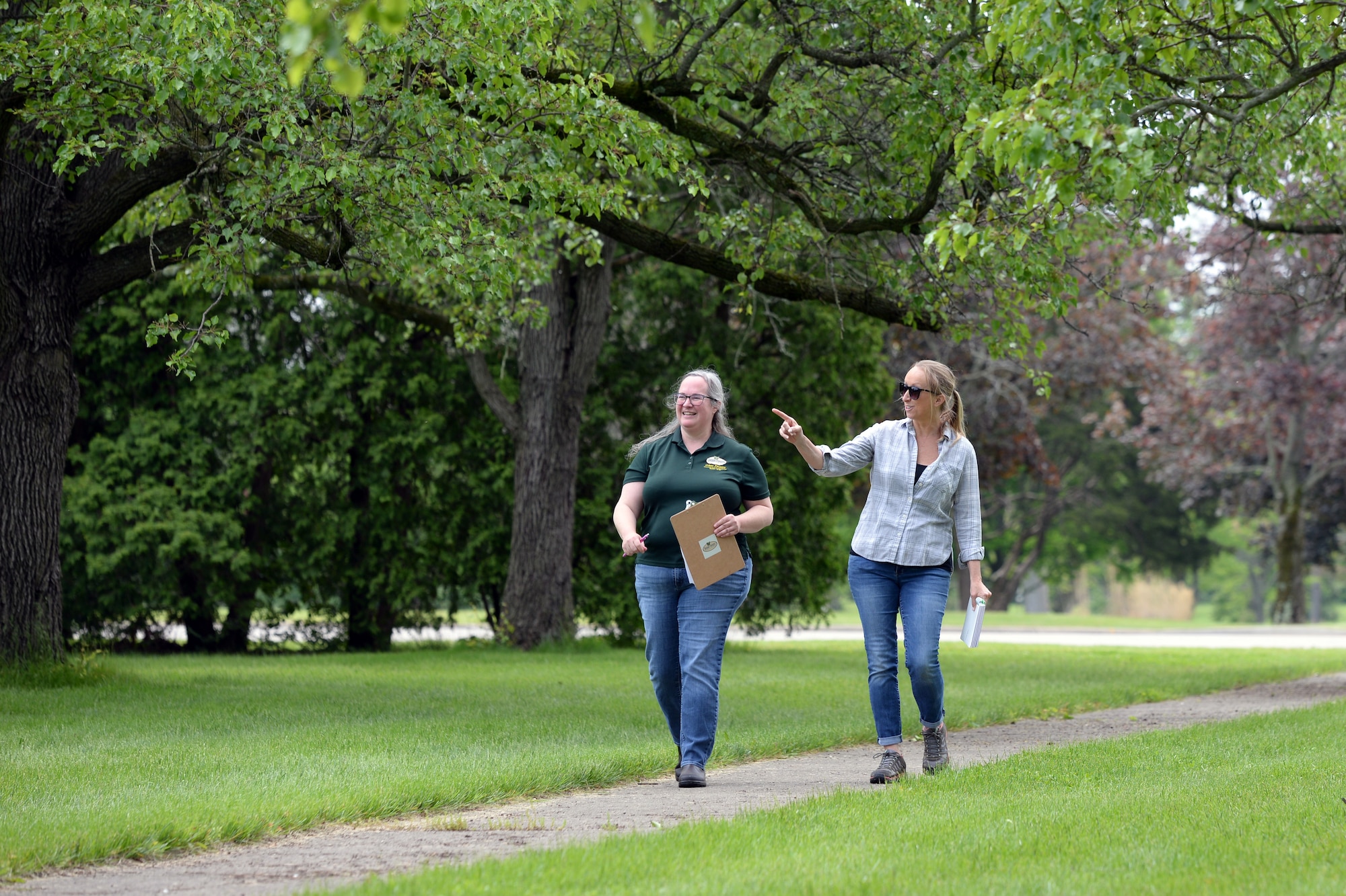 Wendi Van Buren, a regional urban forester with the Ohio Department of Natural Resources, left, and Danielle Trevino, a biological scientist with the 88th Civil Engineer Group, study the trees near the Turtle Pond at Wright-Patterson Air Force Base, Ohio on May 18, 2021. The 88 CEG has partnered with the ODNR Division of Forestry to design a tree planting strategy for Wright-Patt. (U.S. Air Force photo by Ty Greenlees)