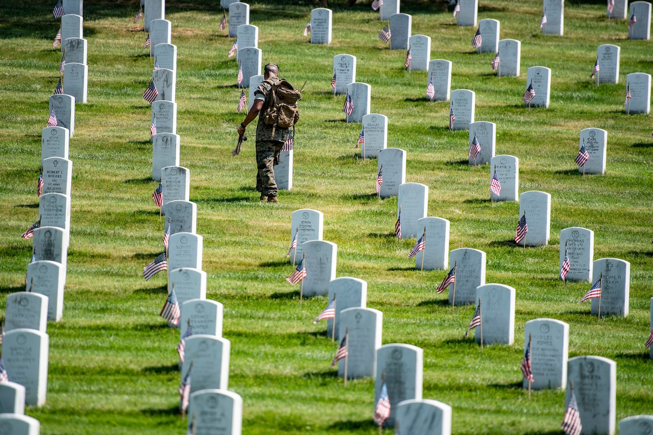 Service members place flags on headstones.