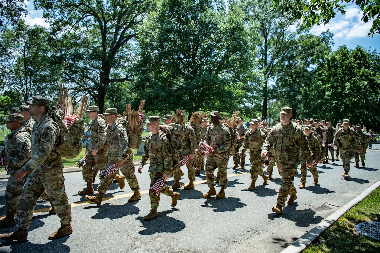 Service members place flags on headstones.