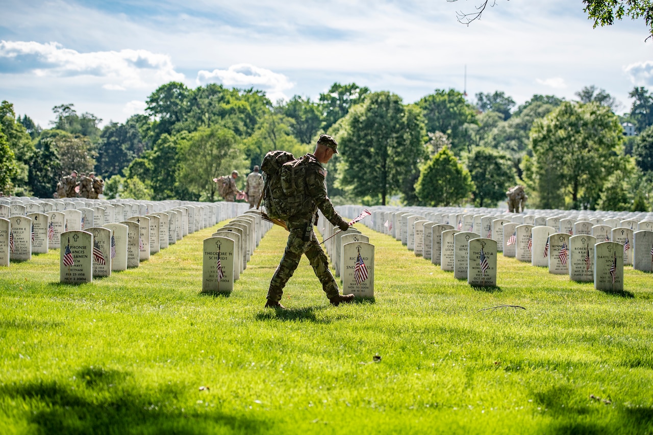 Service members place flags on headstones.