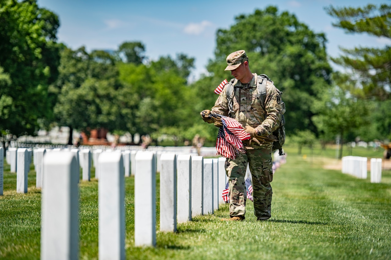 Service members place flags on headstones.