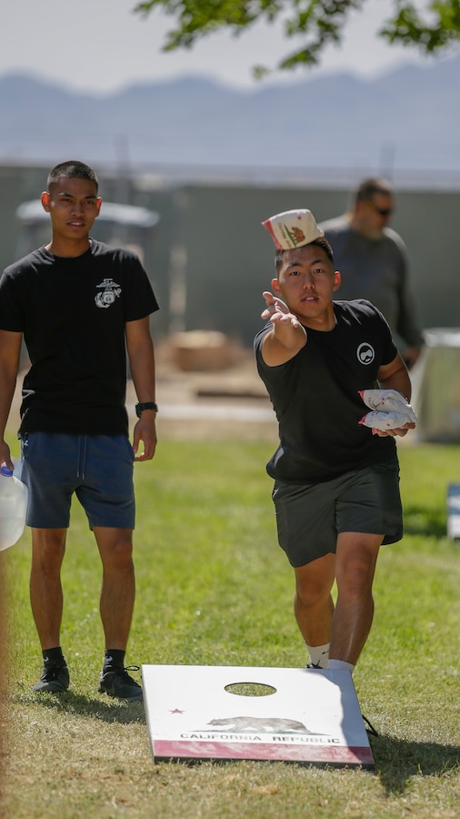 Sgt. Cheng Vang (right), supply administrator, tosses a beanbag during a game of cornhole during 1st Force Storage Battalion's first Employee Recognition Day, since 2019, held at Marine Corps Logistics Base Barstow, California, May 26, 2021. (U.S. Marine Corps photo by Jack J. Adamyk)