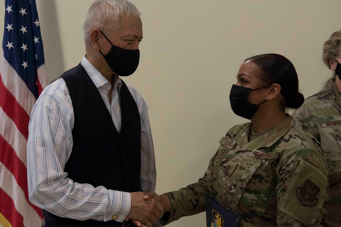The Honorable Sichan Siv, former Ambassador to the United Nations, shakes hands with Tech. Sgt. Jamie Coffee during a commissioning announcement event at Travis Air Force Base, California.