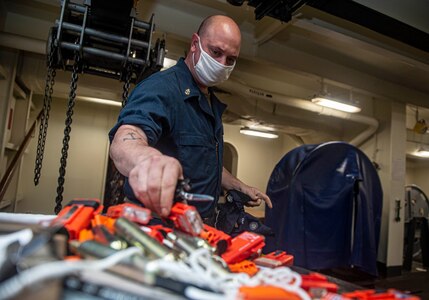 Boatswain's Mate Aaron Wilson, from Fayetteville, Arkansas, removes distress marker lights during maintenance on abandon ship life preservers in the fo'c's'le of the Nimitz-class aircraft carrier USS Harry S. Truman (CVN 75) during sea trials after completing an extended carrier incremental availability.