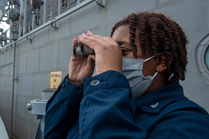 Aviation Aerographer's Mate 3rd Class Asia Edmond, from Newark, New Jersey, uses a pair of binoculars to observe weather patterns from the signal bridge aboard the Nimitz-class aircraft carrier USS Harry S. Truman (CVN 75) during sea trials after completing an extended carrier incremental availability.