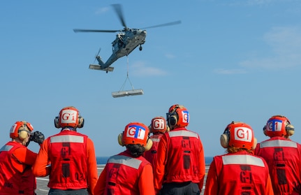 Sailors stand by as an MH-60S Sea Hawk helicopter, attached to the "Dragon Slayers" of Helicopter Sea Combat Squadron (HSC) 11, transports cargo from Lewis and Clark-class dry cargo ship USNS Medgar Evers (T-AKE13) to the Nimitz-class aircraft carrier USS Harry S. Truman (CVN 75) during sea trials after completing an extended carrier incremental availability.