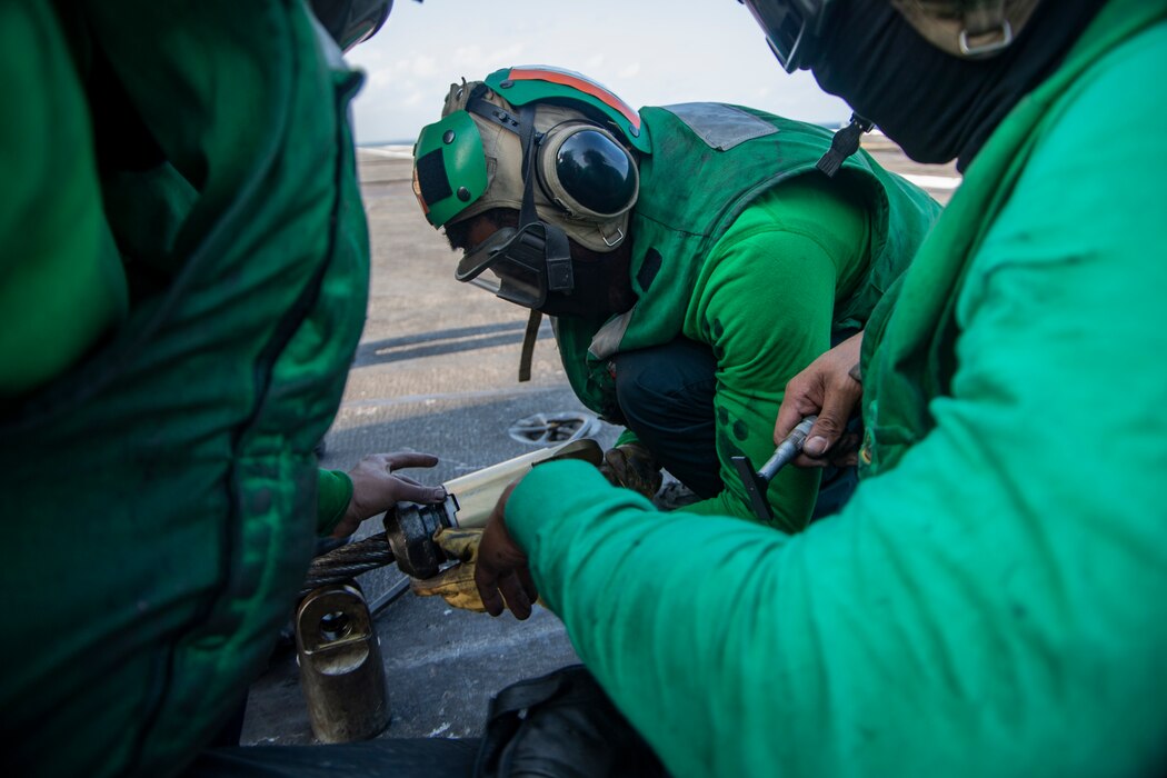 Aviation Boatswain's Mate (Equipment) 1st Class Carlouie Claro, from Manila, Philippines, attaches an arresting gear cable barrel onto an arresting gear cable on the flight deck of the Nimitz-class aircraft carrier USS Harry S. Truman (CVN 75) during carrier qualifications after completing an extended incremental availability.
