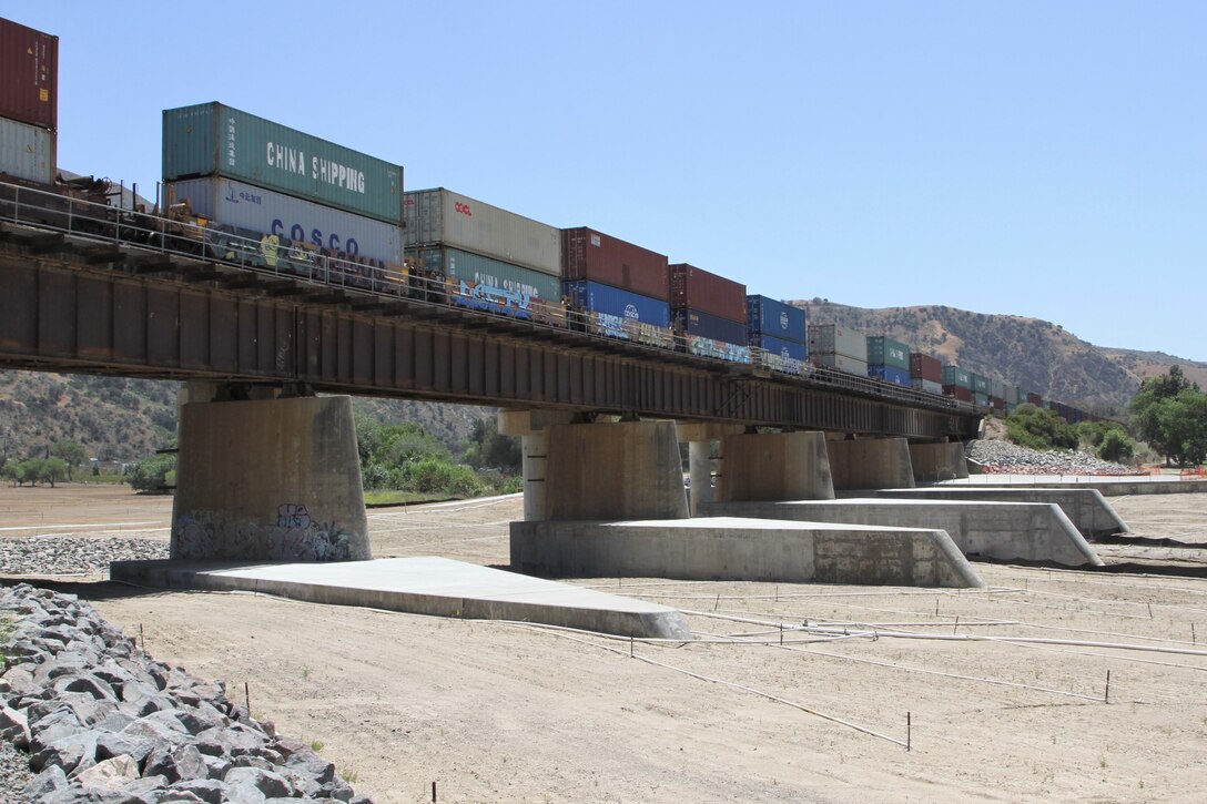 Construction is now complete on the BSNF Railroad Bridge Pier Protection Project in Corona, California. Representatives of local, county, state and federal agencies gathered near the Santa Ana River in Corona on May 27, 2021, to mark the project’s official completion. The purpose of the project is to minimize risk to the bridge in flood conditions and during increased water releases from Prado Dam resulting from periods of heavy rainfall. The project, which was awarded in 2017, is the result of a partnership among the U.S. Army Corps of Engineers, the Riverside County Flood Control and Water Conservation District, Orange County Public Works and San Bernardino County. The completion of the bridge pier protection feature is part of the Santa Ana River Mainstem Project, which is a fully integrated flood-risk management system that protects more than 3 million residents of Riverside, Orange and San Bernardino counties, several major freeways, the rail system itself, and an array of businesses and infrastructure downstream of Prado Dam.