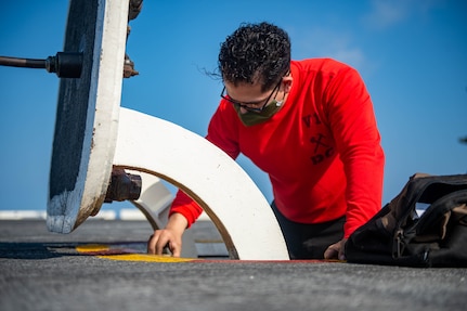 Aviation Boatswain's Mate (Handling) 3rd Class Joseph Vasquez, from Houston, cleans a hatch on the flight deck of the Nimitz-class aircraft carrier USS Harry S. Truman (CVN 75) during sea trials after completing an extended carrier incremental availability.