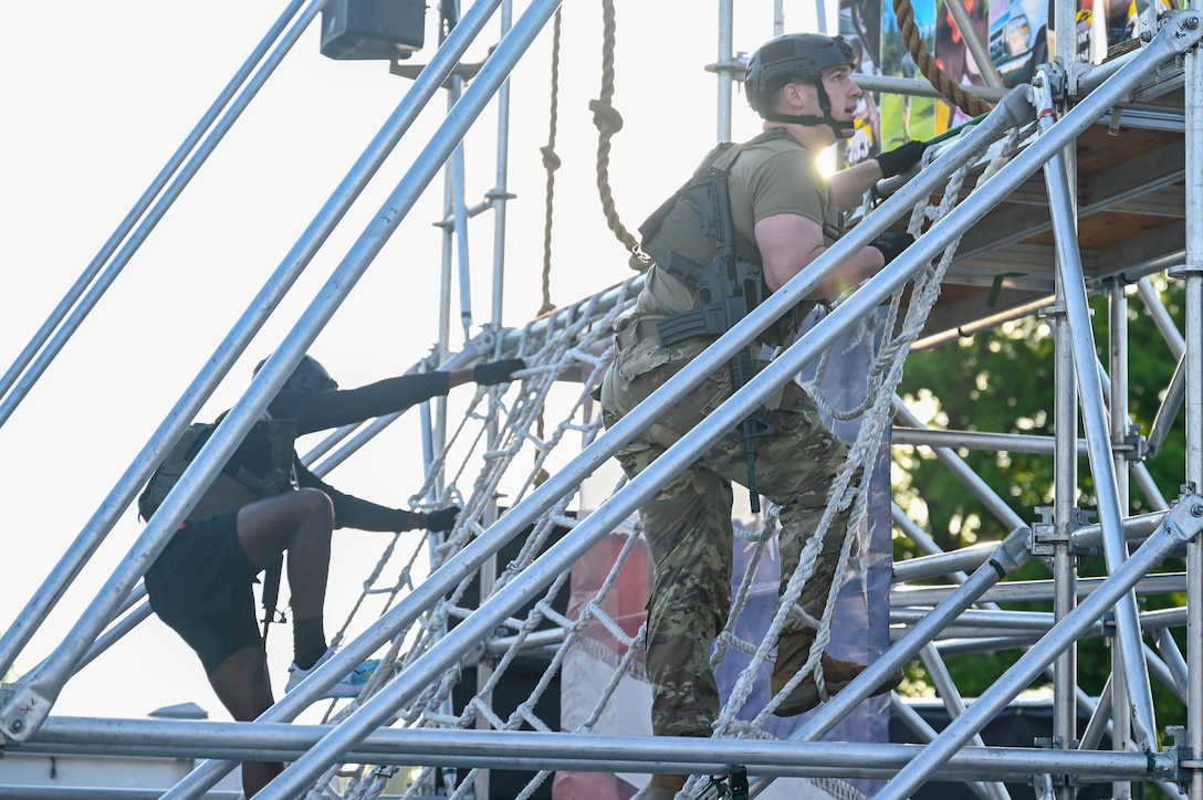 Two U.S. Soldiers climb a cargo net during the Military Battle Challenge obstacle course at Joint Base Langley-Eustis, Virginia, May 22, 2021. The Military Battle Challenge is a timed obstacle course that tests Soldiers' abilities over nine separate tasks. (U.S. Air Force photo by Senior Airman John Foister)