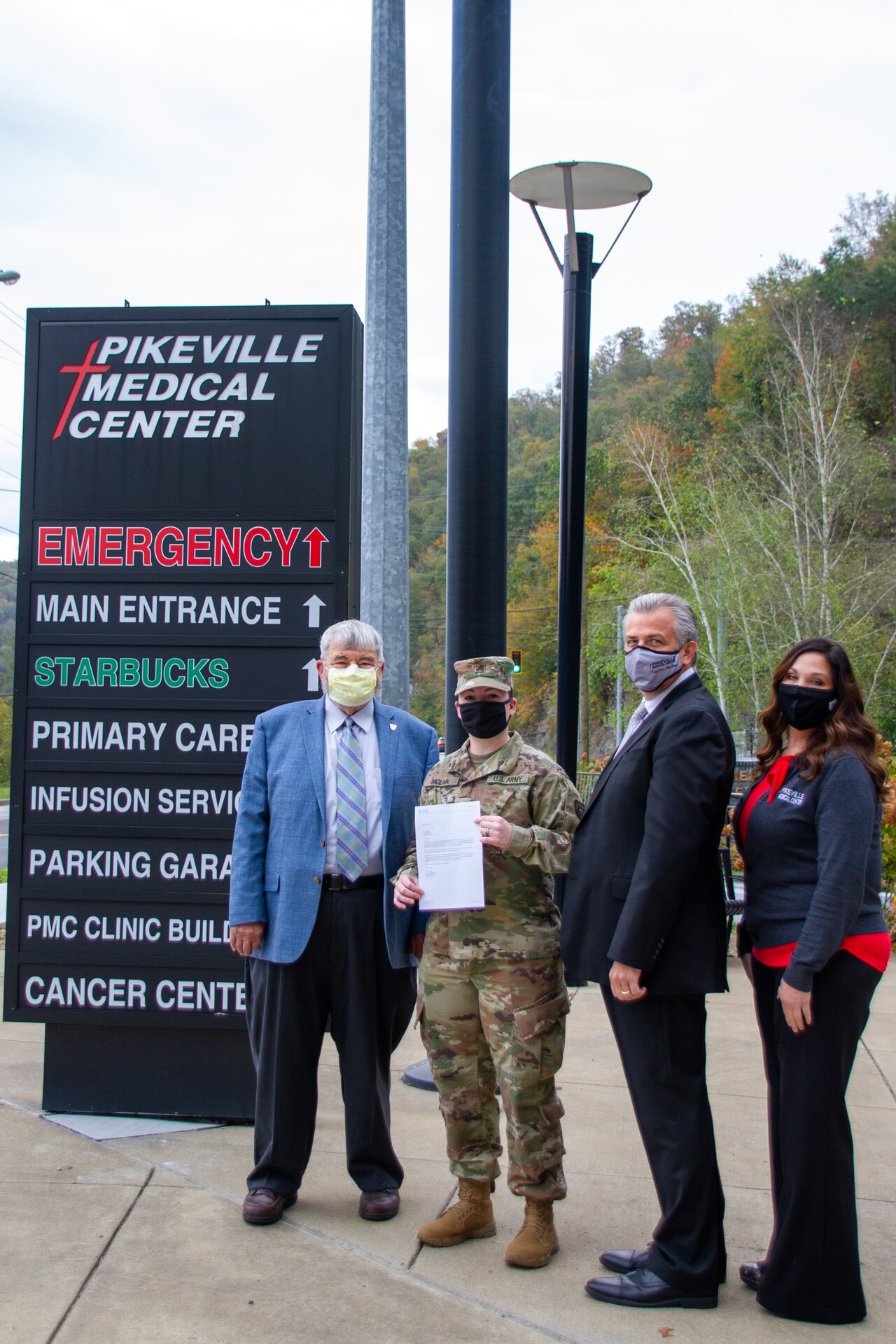Kentucky Army National Guard Sgt. Janay McLain, squad leader with 2061st Multi-Role Bridge Company, poses for a photograph while holding her nursing school acceptance letter with Pikeville Medical Center administrators in Pikeville, KY October 25, 2021. The Kentucky National Guard has been requested to provide support to hospital staff across the Commonwealth.  (U.S. Army National Guard photo by Sgt. Matt Damon)