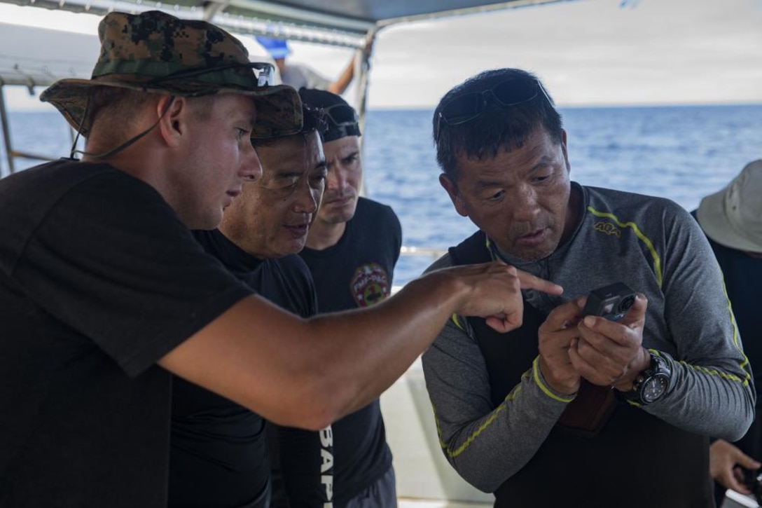 U.S. Marines with Task Force Koa Moana 21, I Marine Expeditionary Force, and members of the Japanese Mine Action Service review photos of man-made mine-like objects taken off the coast of the Republic of Palau, Oct. 20, 2021. Task Force Koa Moana 21 provides opportunities to work with explosive ordnance disposal teams, maritime law enforcement, medical professionals, and humanitarian assistance organizations.