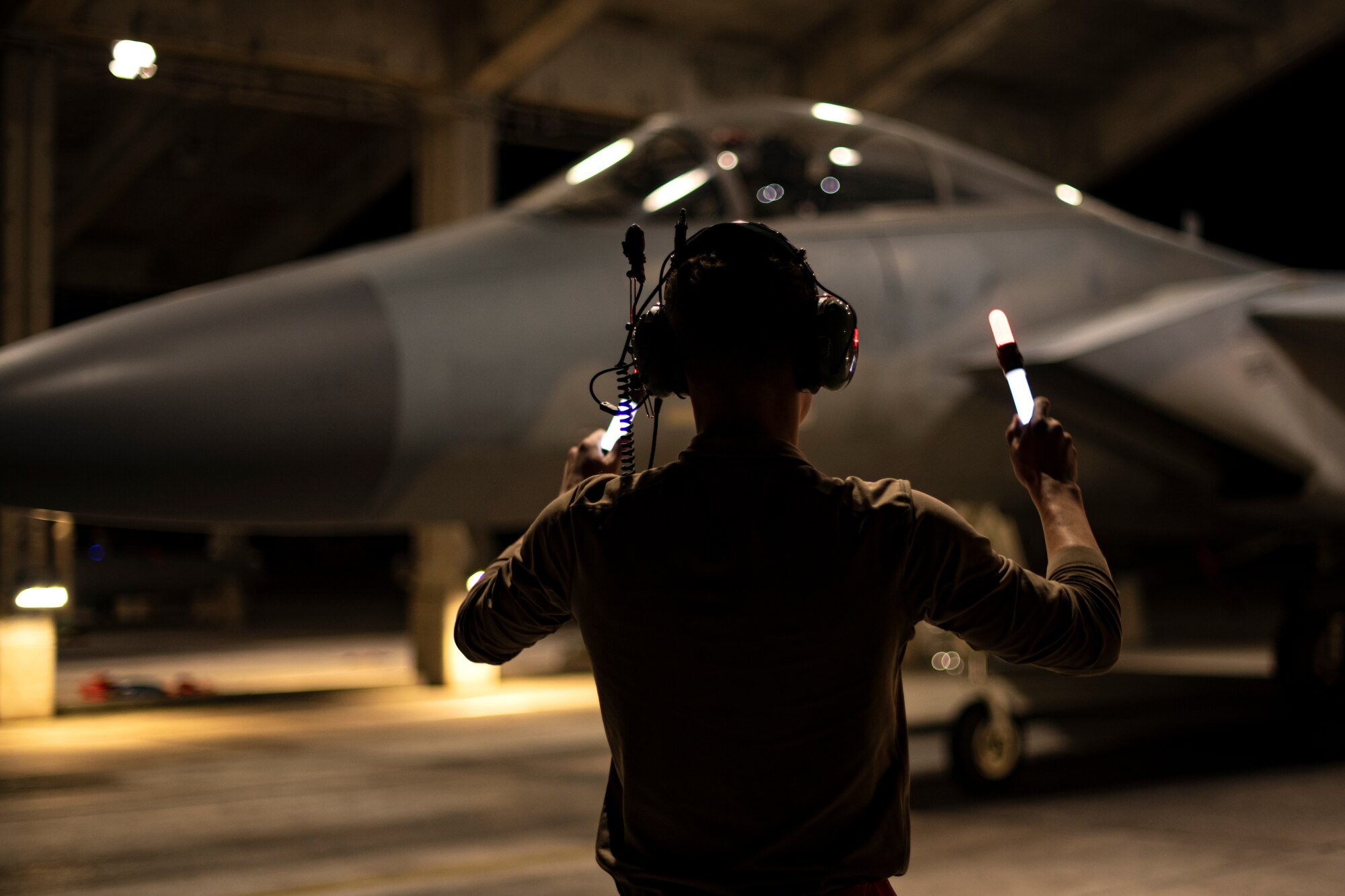 U.S. Air Force Senior Airman Jonah Juve, 44th Aircraft Maintenance Unit crew chief, marshals an F-15C Eagle into the aircraft shelter after a training sortie in support of Exercise Southern Beach at Kadena Air Base, Japan, Oct. 28, 2021. This was the first time since the inception of Southern Beach where the majority of the mission sets and a Japan-U.S. training program were conducted during night hours. (U.S. Air Force photo by Senior Airman Jessi Monte)