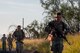 Group of people are rucking through a dirt road.