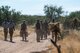 Group of people walking down a dirt road.