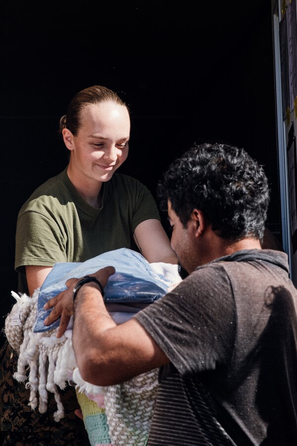 U.S. Marine Corps Cpl. Katherine Duncan, a warehouse clerk assigned to Task Force Pickett, distributes cold weather supplies to Afghan guests in Fort Pickett, Virginia, Oct. 23, 2021. Task Force Pickett will be distributing over 70,000 articles of clothing with thousands of blankets and linen sets to help Afghan guests prepare for the upcoming winter months.  The Department of Defense, through U.S. Northern Command, and in support of the Department of Homeland Security, is providing transportation, temporary housing, medical screening, and general support for at least 50,000 Afghan evacuees at suitable facilities, in permanent or temporary structures, as quickly as possible. This initiative provides Afghan personnel essential support at secure locations outside Afghanistan. (U.S. Marine Corps photo by Lance Cpl. Zachary Zephir)