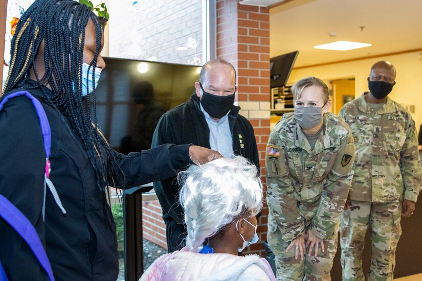 Col. Paige M. Jennings, U.S. Army Financial Management Command commander, Barry W. Hoffman, USAFMCOM deputy to the commander, and Command Sgt. Maj. Kenneth F. Law, USAFMCOM senior enlisted advisor, talk with a costumed student at a local daycare facility next to the Maj. Gen. Emmett J. Bean Federal Center Oct. 29, 2021. The USAFMCOM leadership team delivered 100 festive treat bags to students at the center. (U.S. Army photo by Mark R. W. Orders-Woempner)