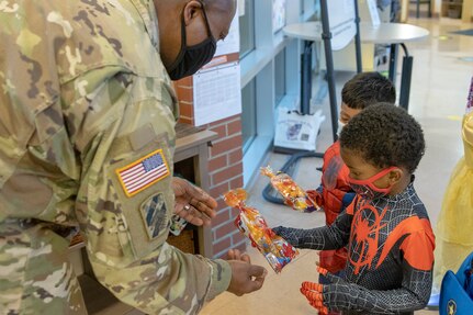 Command Sgt. Maj. Kenneth F. Law, U.S. Army Financial Management Command senior enlisted advisor, gives treat bags to costumed students at a local daycare facility next to the Maj. Gen. Emmett J. Bean Federal Center Oct. 29, 2021. Law, along with Col. Paige M. Jennings, USAFMCOM commander, and Barry W. Hoffman, USAFMCOM deputy to the commander, delivered 100 festive treat bags to students at the center. (U.S. Army photo by Mark R. W. Orders-Woempner)