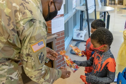 Command Sgt. Maj. Kenneth F. Law, U.S. Army Financial Management Command senior enlisted advisor, gives treat bags to costumed students at a local daycare facility next to the Maj. Gen. Emmett J. Bean Federal Center Oct. 29, 2021. Law, along with Col. Paige M. Jennings, USAFMCOM commander, and Barry W. Hoffman, USAFMCOM deputy to the commander, delivered 100 festive treat bags to students at the center. (U.S. Army photo by Mark R. W. Orders-Woempner)