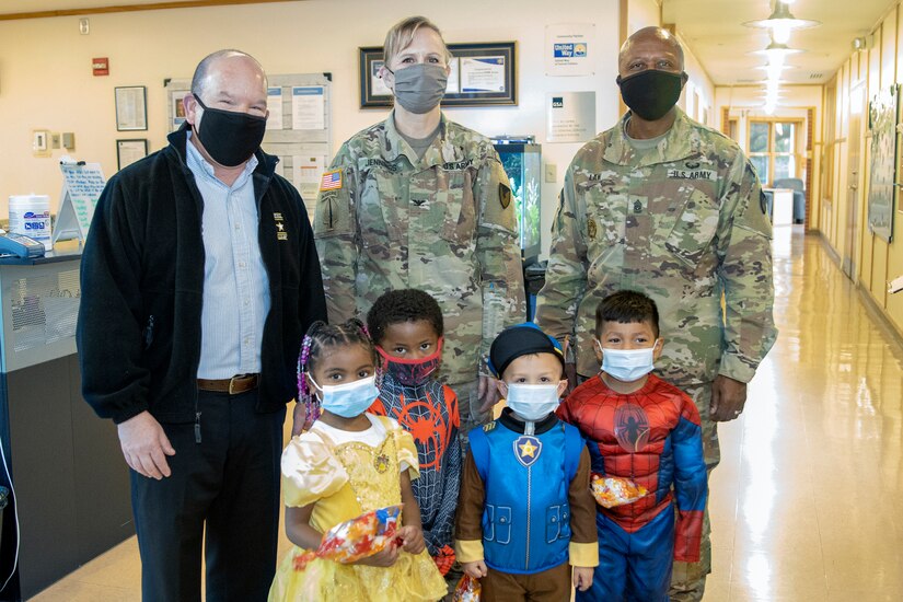 Col. Paige M. Jennings, U.S. Army Financial Management Command commander, Barry W. Hoffman, USAFMCOM deputy to the commander, and Command Sgt. Maj. Kenneth F. Law, USAFMCOM senior enlisted advisor, pose for a photo with costumed students at a local daycare facility next to the Maj. Gen. Emmett J. Bean Federal Center Oct. 29, 2021. The USAFMCOM leadership team delivered 100 festive treat bags to students at the center. (U.S. Army photo by Mark R. W. Orders-Woempner)