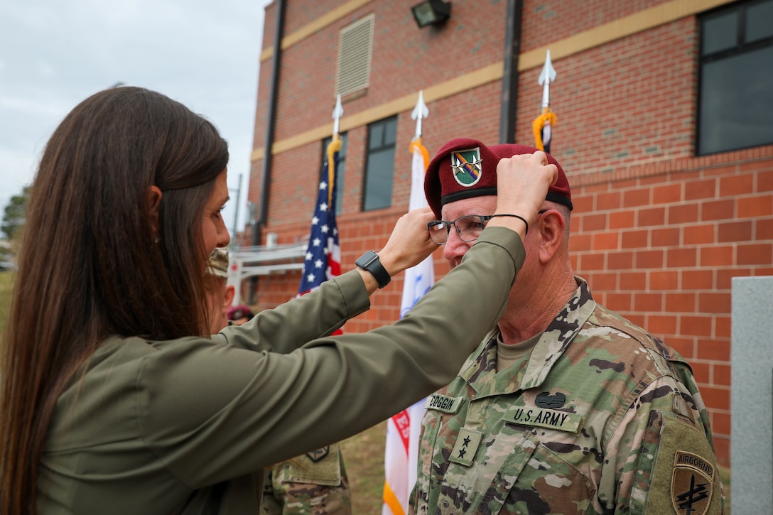 Kristin A. Coggin, daughter of Maj. Gen. Jeffrey C. Coggin, commanding general, U.S. Army Civil Affairs and Psychological Operations Command (Airborne), assists her father in exchanging his one star beret for the appropriate two star beret during his promotion ceremony, Oct. 25, 2021, Fort Bragg, N.C.