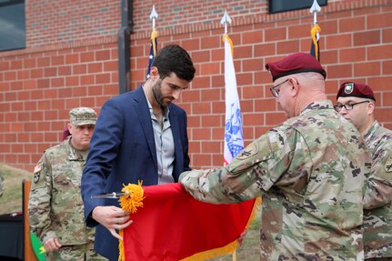 Maj. Gen. Jeffrey C. Coggin, commanding general, U.S. Army Civil Affairs and Psychological Operations Command (Airborne) is assisted by his son, Kevin Coggin, during the uncasing of his two-star flag during his promotion ceremony, Oct. 25, 2021, Fort Bragg, N.C.