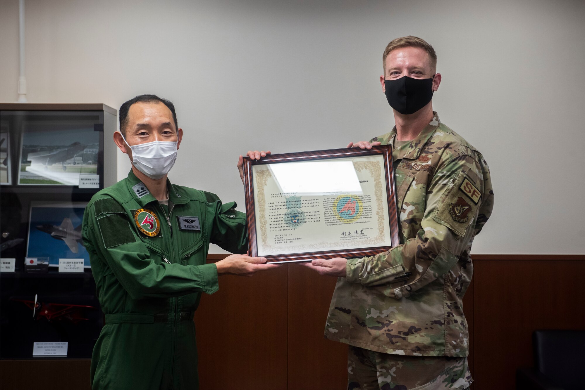 Military members in uniform hold a certificate.