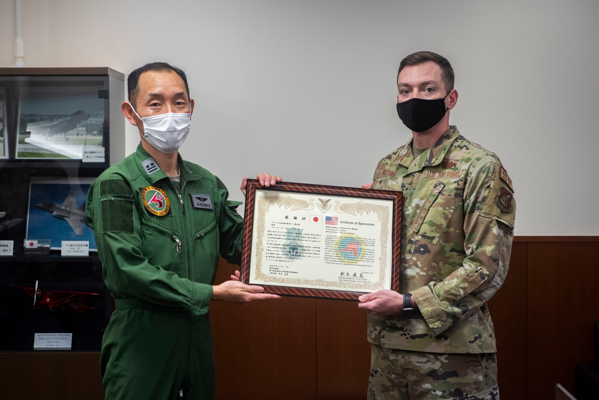 Military members in uniform hold a certificate.