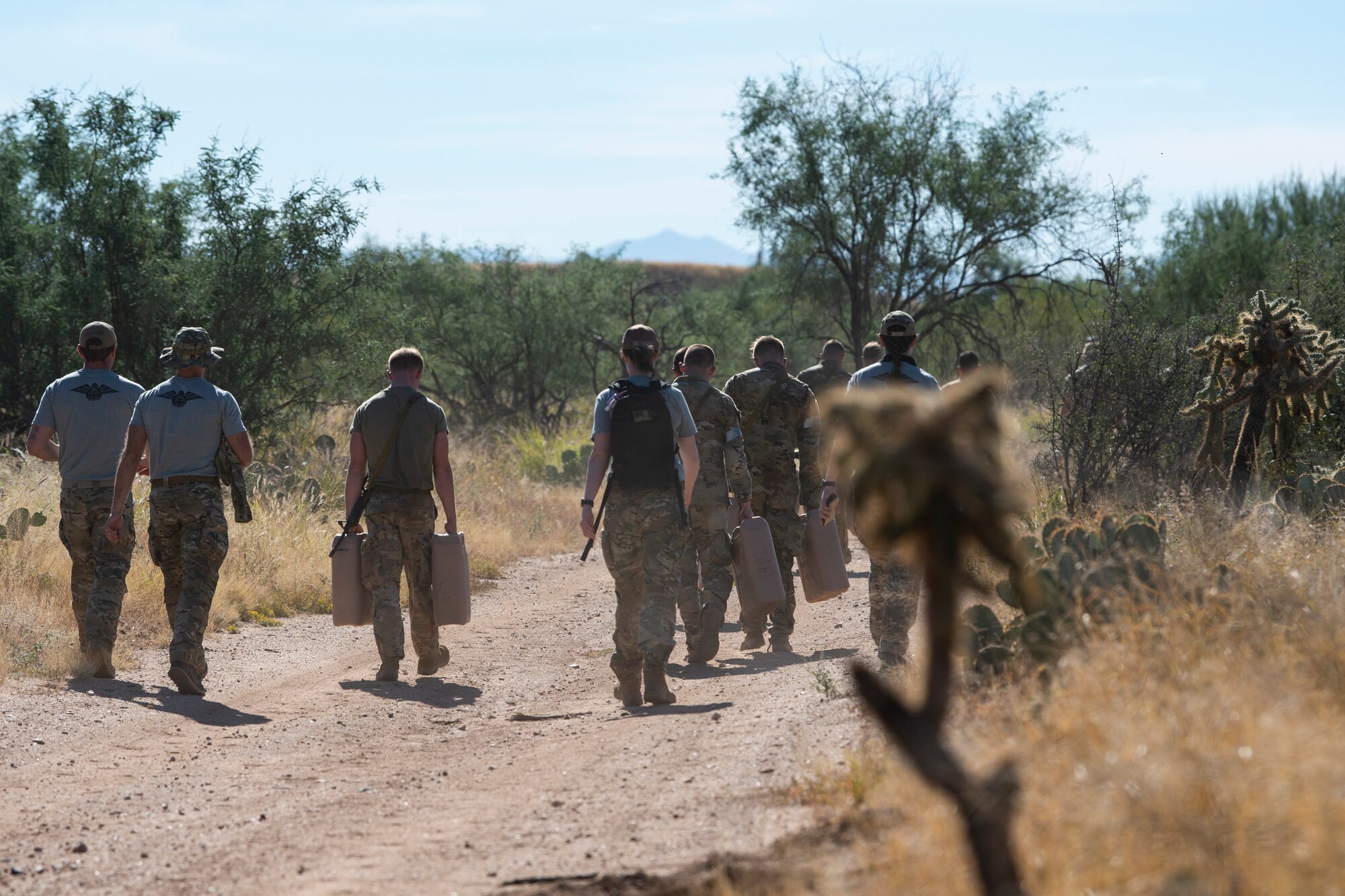 Group of people walking down a dirt road.