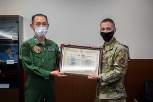 Military members in uniform hold a certificate.