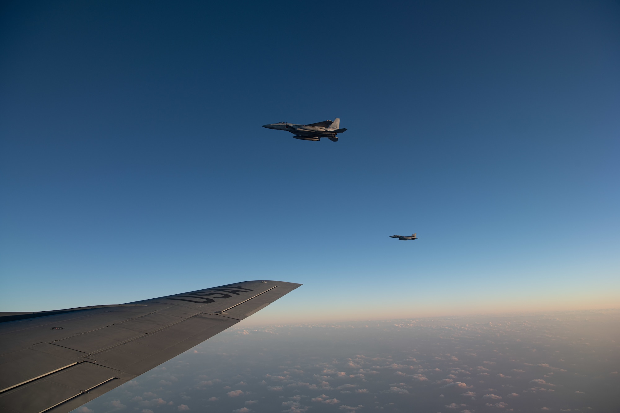 Two Japan Air Self-Defense Force F-15DJ Eagles fly next to a U.S. Air Force KC-135 Stratotanker from the 909th Air Refueling Squadron after refueling over the Pacific Ocean during Exercise Southern Beach, Oct. 28, 2021. The large force exercise primarily focused on offensive and defensive counter air operations, personnel rescue, and airdrop missions. (U.S. Air Force photo by Staff Sgt. Savannah L. Waters)