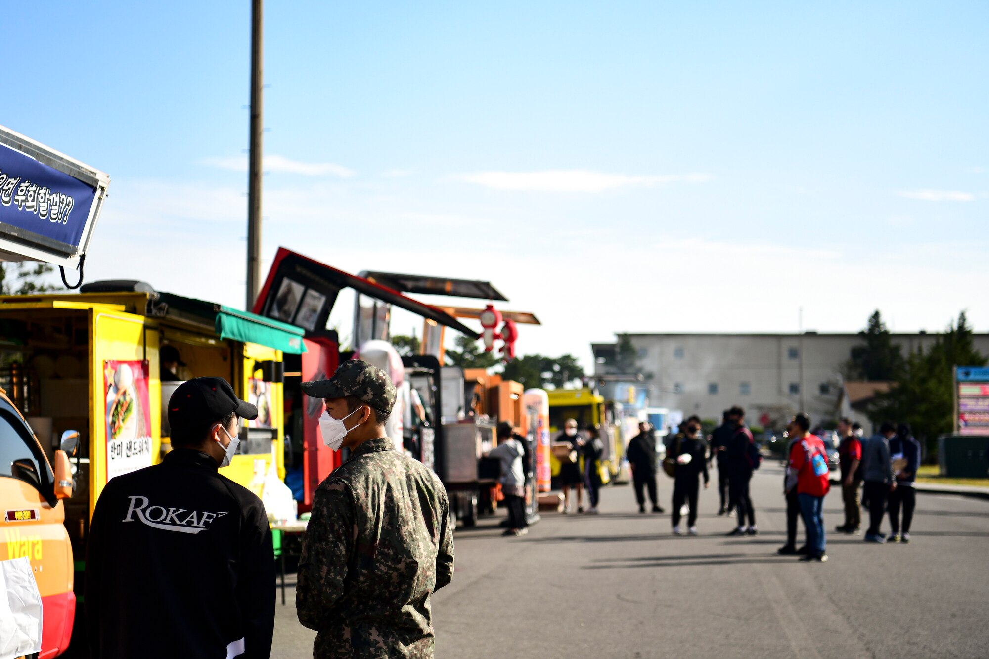 Two Republic of Korea Air Force members chatting alongside food trucks.