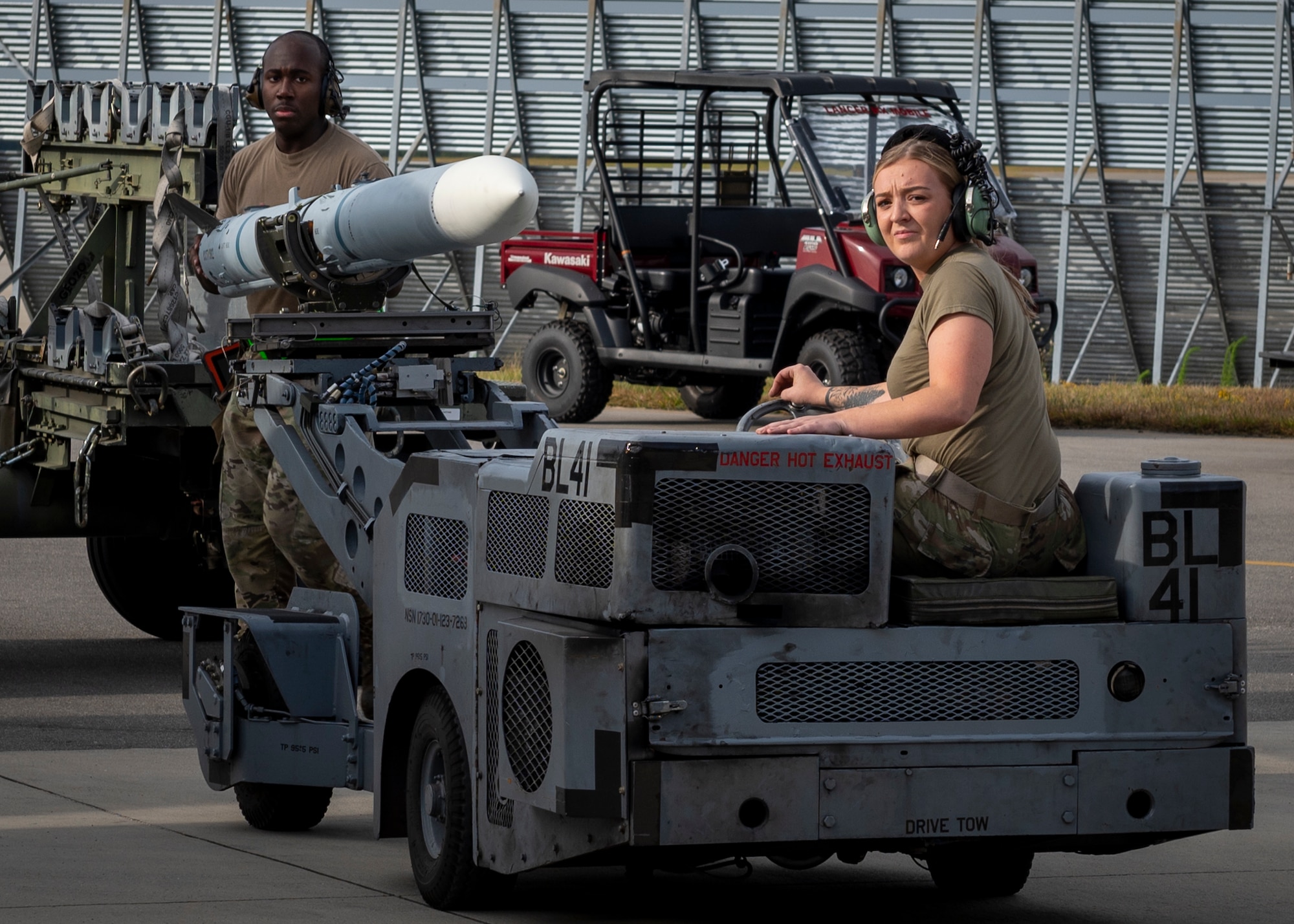 A load crew team chief, left, steadies an AIM-120 missile as the load crew three man drives the MJ-1 bomb lift truck during a load crew competition at Seymour Johnson Air Force Base, North Carolina, Oct. 21, 2021.