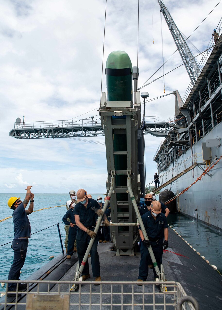 SAIPAN (Oct. 22, 2021) Sailors assigned to the Los Angeles-class fast attack submarine USS Hampton (SSN 767) load a MK-48 inert training shape alongside the submarine tender USS Frank Cable (AS 40) during a weapons handling exercise at the island of Saipan, Commonwealth of the Northern Mariana Islands, Oct. 22. Frank Cable is on patrol conducting expeditionary maintenance and logistics in support of national security in the 7th Fleet area of operations. (U.S. Navy photo by Mass Communication Specialist 1st Class Charlotte C. Oliver)