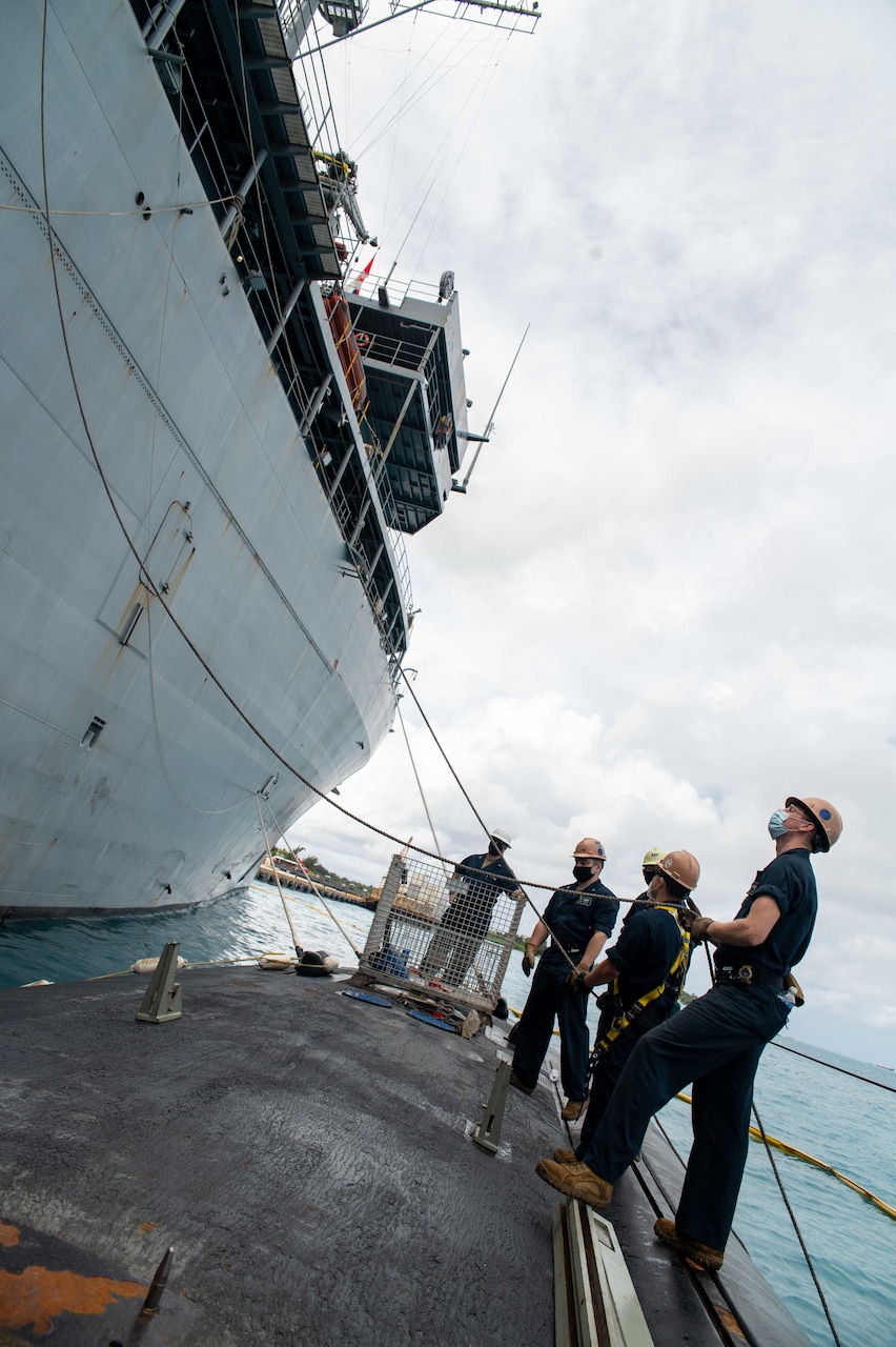 SAIPAN (Oct. 22, 2021) Sailors assigned to the Los Angeles-class fast attack submarine USS Hampton (SSN 767) handle lines during a weapons handling exercise involving the transfer of a MK-48 inert training shape alongside the submarine tender USS Frank Cable (AS 40) at the island of Saipan, Commonwealth of the Northern Mariana Islands, Oct. 22. Frank Cable is on patrol conducting expeditionary maintenance and logistics in support of national security in the 7th Fleet area of operations. (U.S. Navy photo by Mass Communication Specialist 1st Class Charlotte C. Oliver)