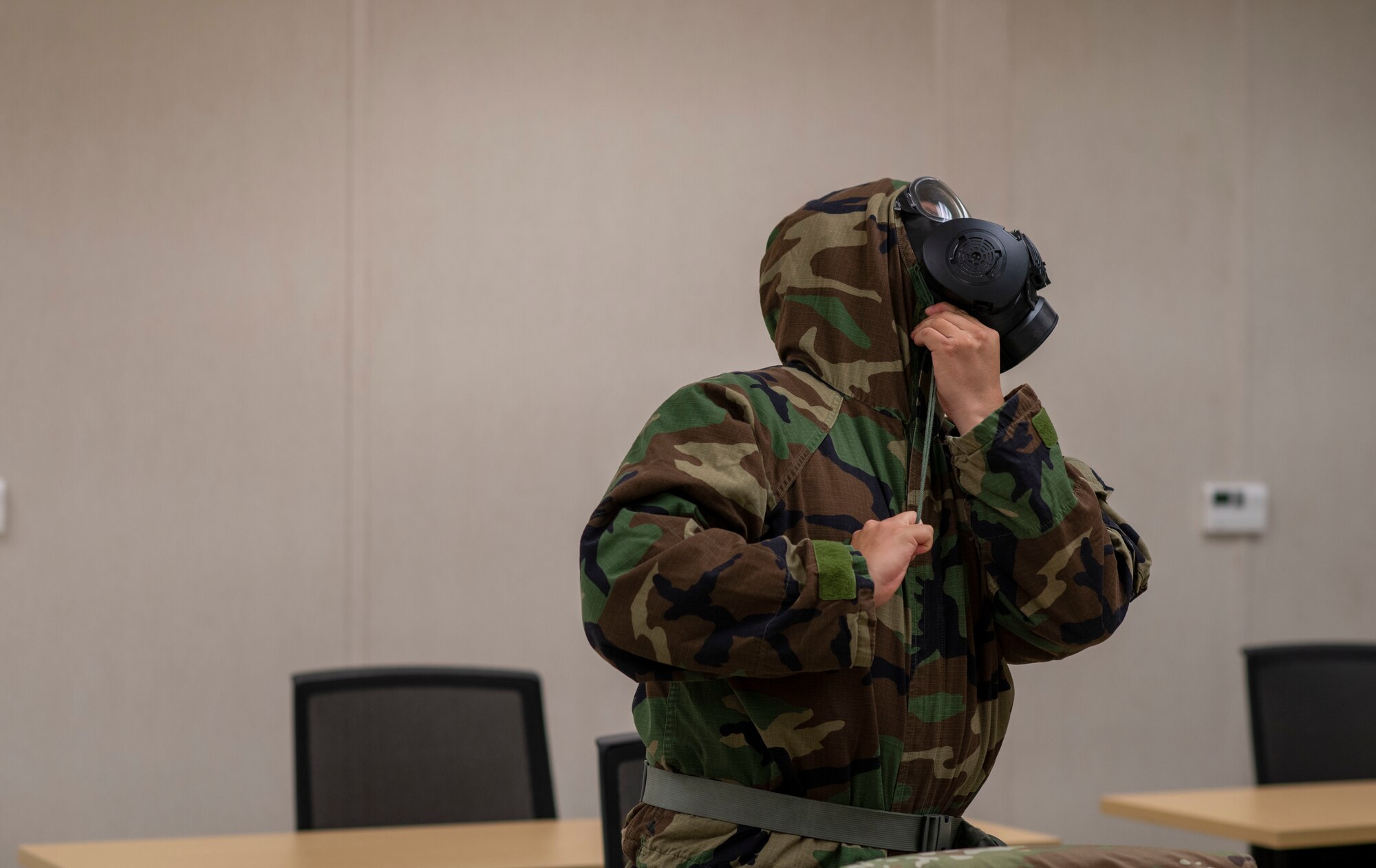 A man tightens a hood around a gasmask