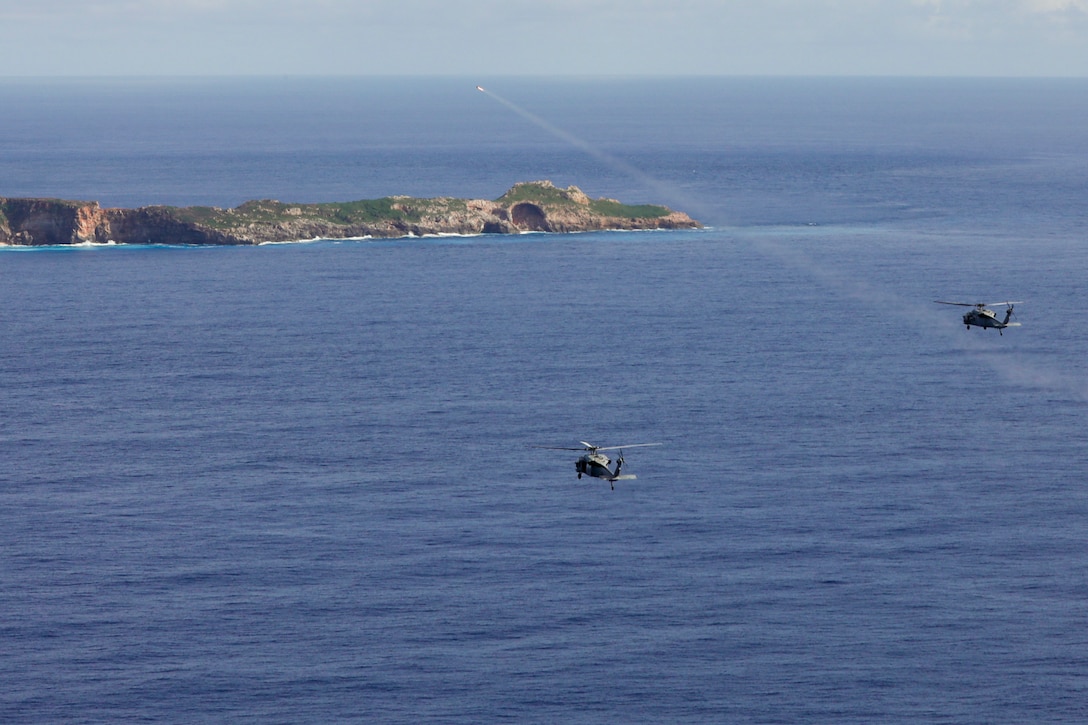 A helicopter launches a missile over a body of water near two other helicopters.