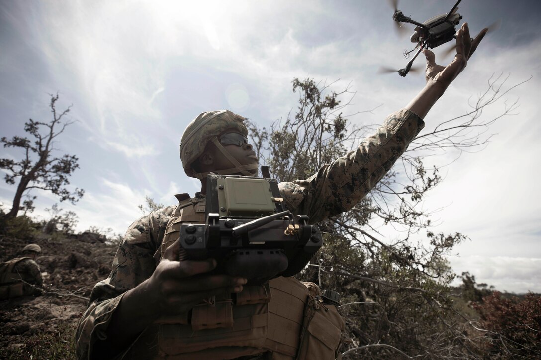 A Marine launches a drone into a field.