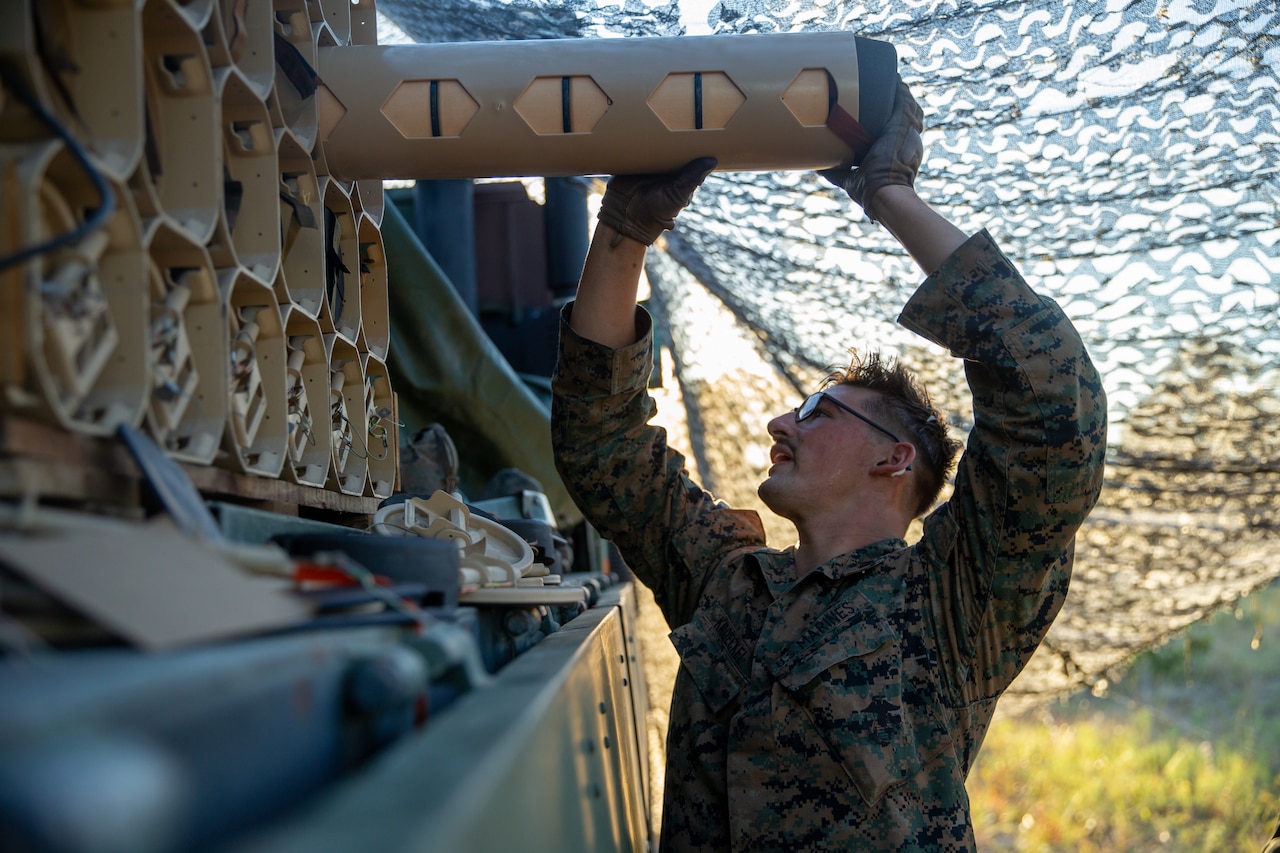 A Marine restocks cargo in a field.