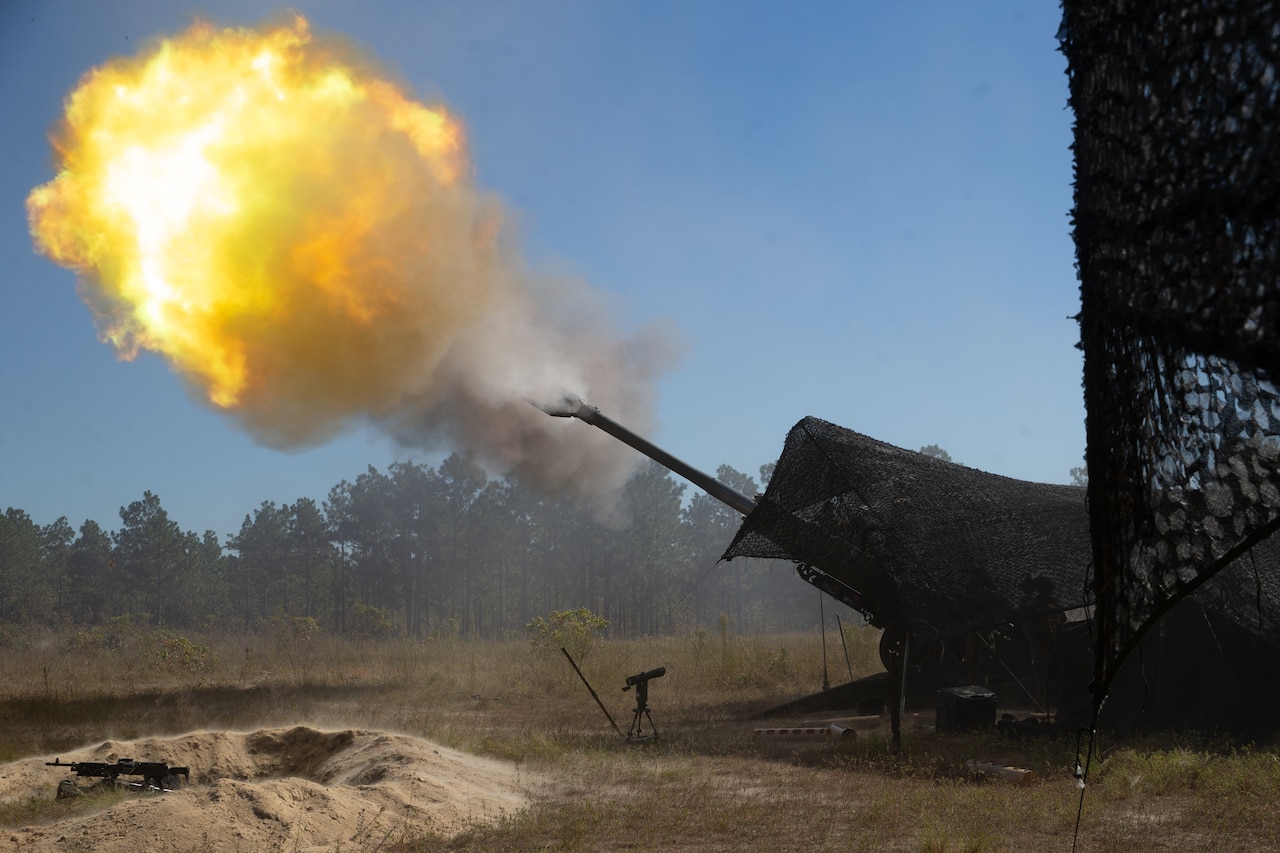 Marines fire a howitzer in a field.