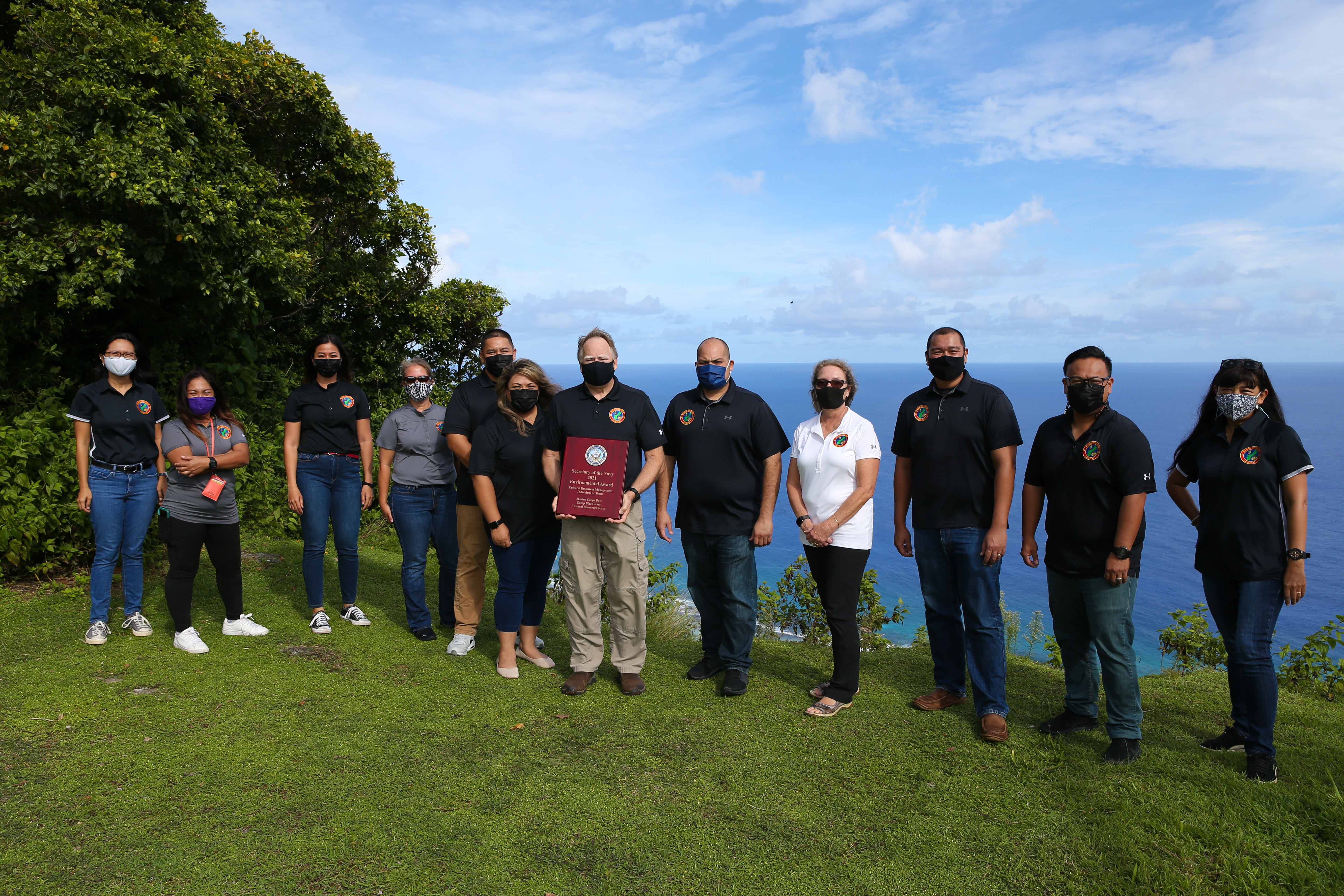 Ronnie Rogers, NAVFAC Marianas Cultural Resources Manager, Marine Corps Base (MCB) Camp Blaz, center, holds the 2021 SECNAV Environmental Award for Cultural Resources Management Individual or Team and poses with the Guam Cultural Resources Team at Tarague Overlook, Guam, Oct. 28, 2021.