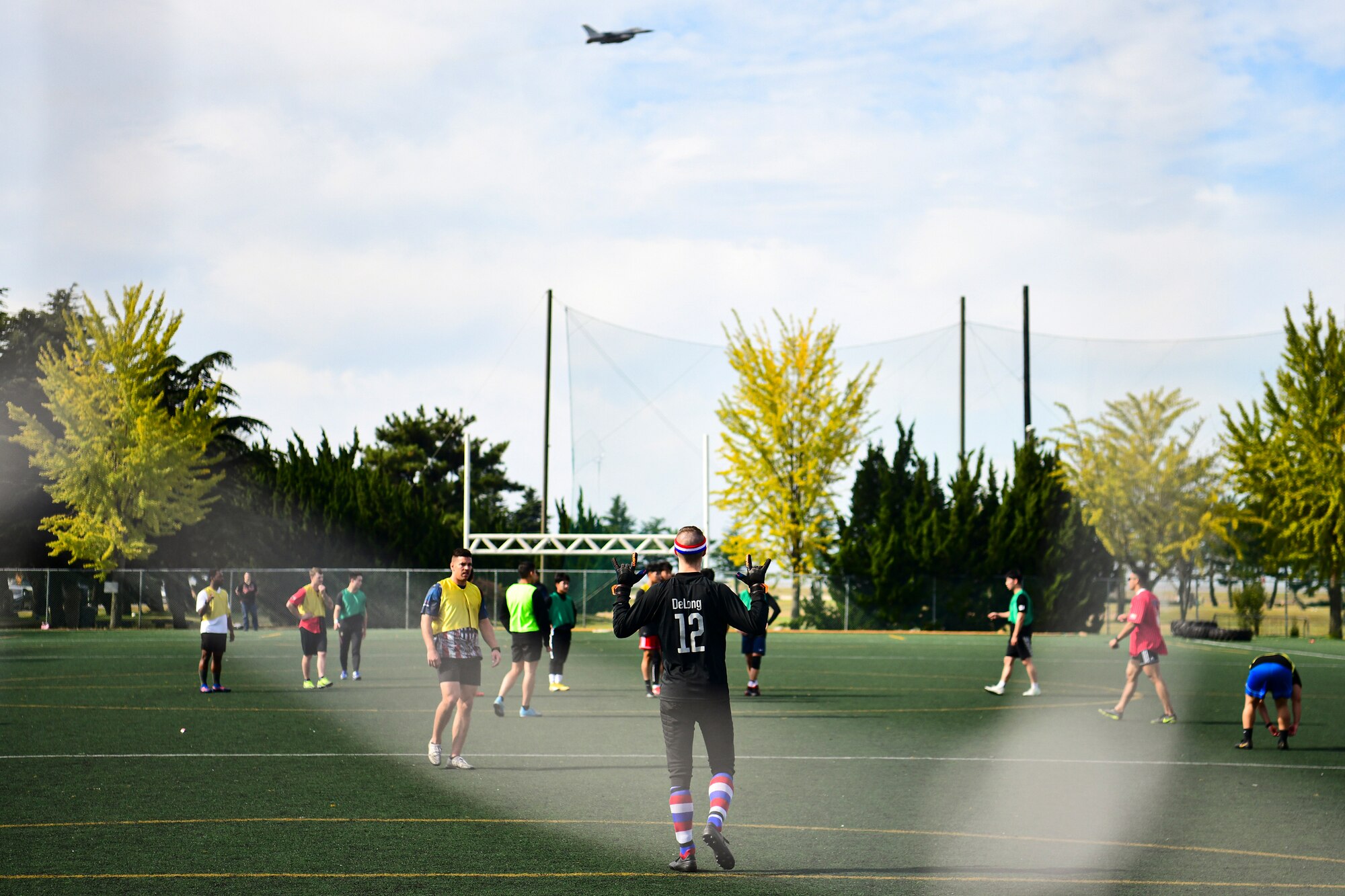 Airmen playing soccer with a jet flying overhead,